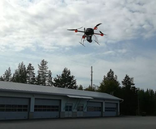 Drone-laite ilmassa ja taustalla näkyy pitkä rakennus.