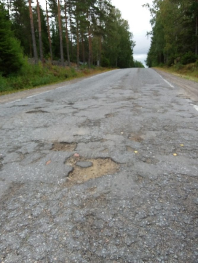 Kuvassa reikäinen asfaltoitu tie.